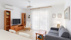 A living room with a sofa, TV, wooden cabinet, and a dining table. - Apartment 'Cozy Sea View Flat' with Sea View, Wi-Fi and Air Conditioning (La Manga)