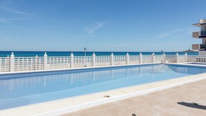 A swimming pool with a white fence, a clear blue sky, and a view of the sea. - Apartment 'Cozy Sea View Flat' with Sea View, Wi-Fi and Air Conditioning (La Manga)