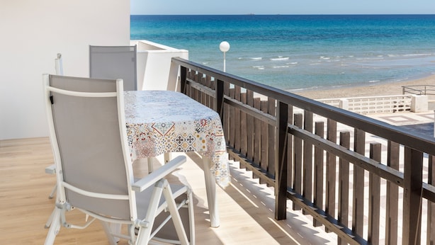 A balcony with a table and chairs, overlooking a beach and the sea. - Apartment 'Cozy Sea View Flat' with Sea View, Wi-Fi and Air Conditioning (La Manga)