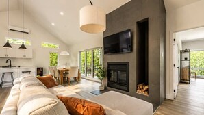 Een moderne woonkamer met een bank, een open haard, een televisie en een eethoek.
