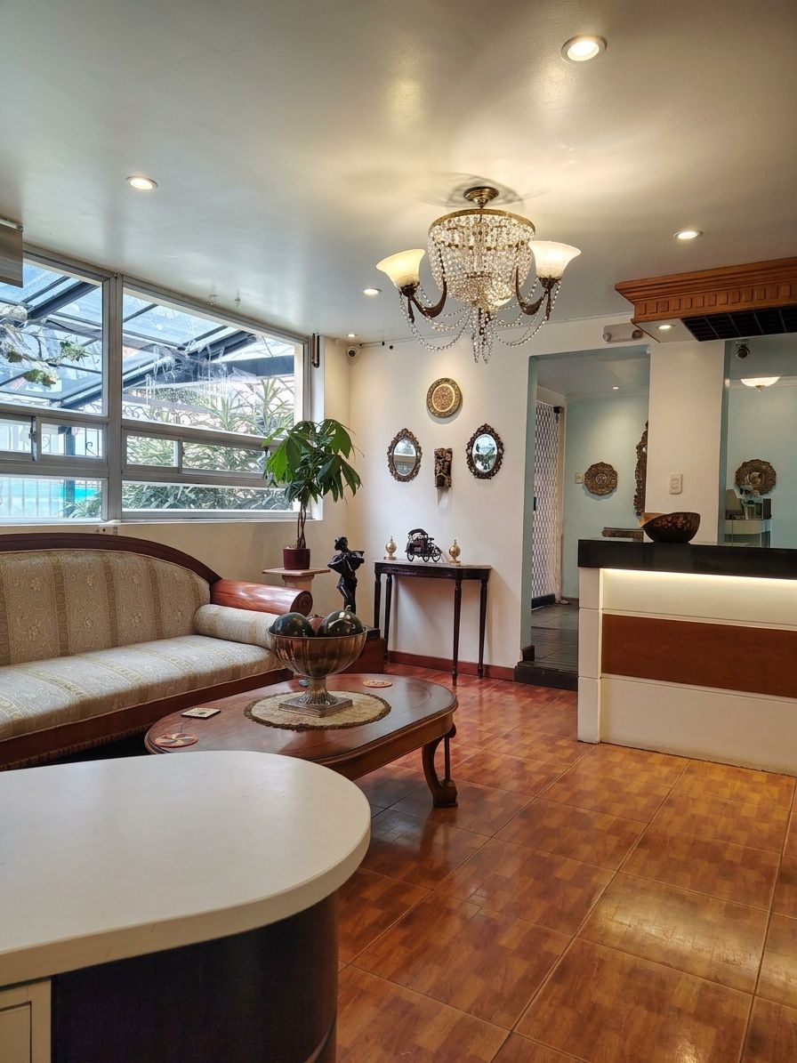 A living room with a sofa, coffee table, and a chandelier. There is a dining area with a table and chairs.