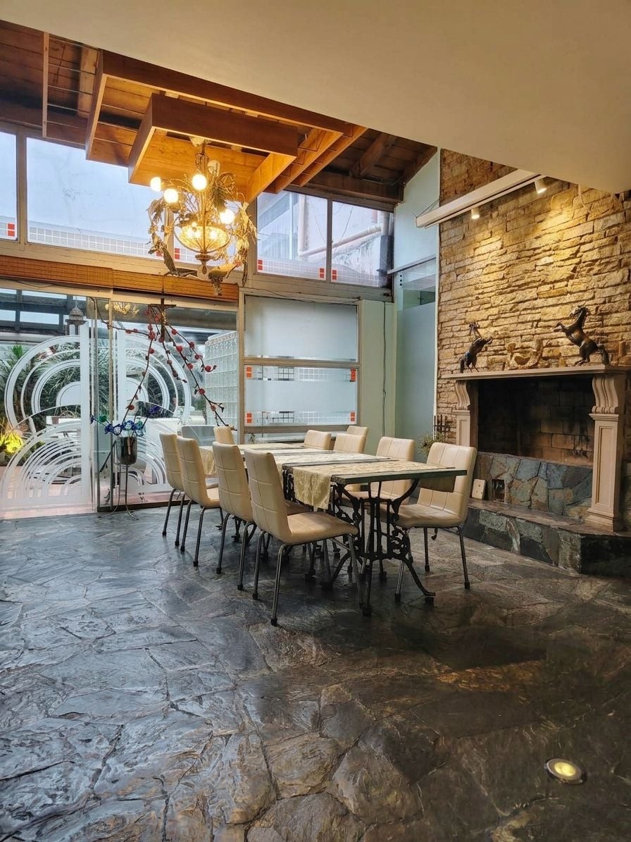 A dining area with a stone floor, a chandelier, and a fireplace.