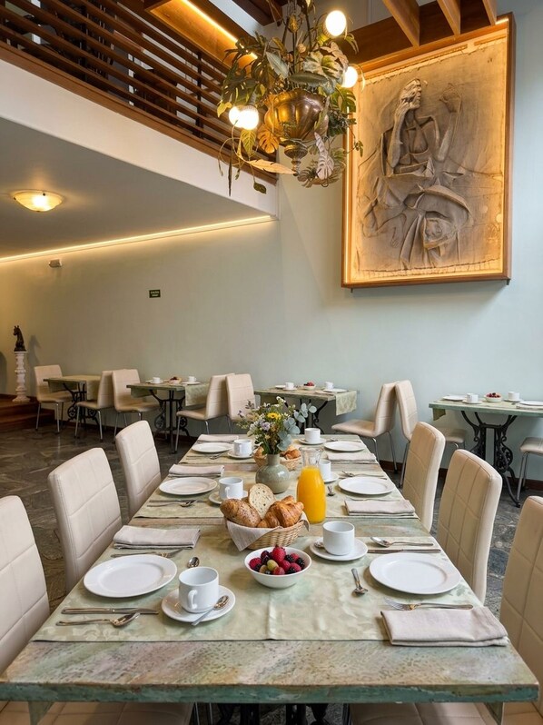A dining area with tables set for breakfast, featuring a variety of fruits and pastries. - CASA LAVIM  (Bogotá)