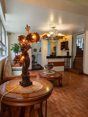 Una sala de estar con piso de madera, un candelabro, una estatua y una escalera.