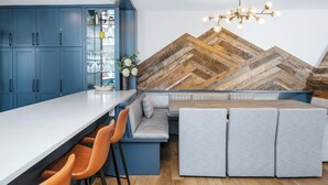 Une cuisine moderne dotée d’un bar intégré, d’un coin salon et d’un mur décoratif en bois disposé en motif chevron.