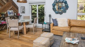 Un salon avec une table en verre, deux fauteuils, un canapé en cuir marron et une table basse sur laquelle sont posés des magazines.