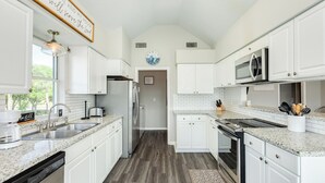 A kitchen with white cabinets, a microwave, a sink, and a clock on the wall. - 2 blocks to beach, 13 mi to Downtown - Dog Friendly & Great for Families! (Galveston)