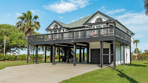 A two-story house with a balcony, a garage, and a well-maintained lawn. - 2 blocks to beach, 13 mi to Downtown - Dog Friendly & Great for Families! (Galveston)
