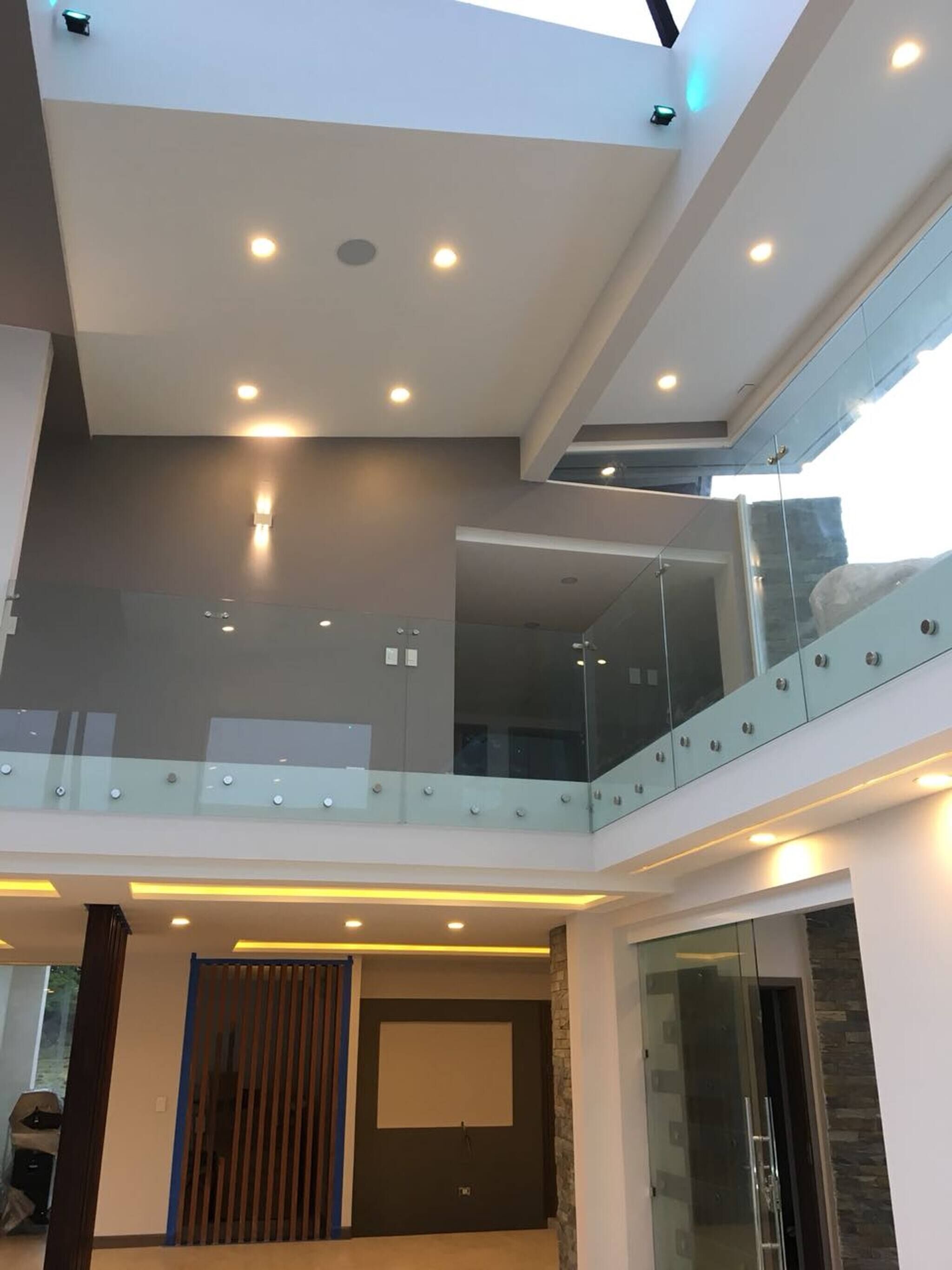 A modern interior with a glass balcony, recessed lighting, and a stone accent wall.