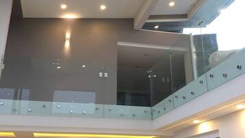 A modern interior with a glass balcony, recessed lighting, and a stone accent wall.