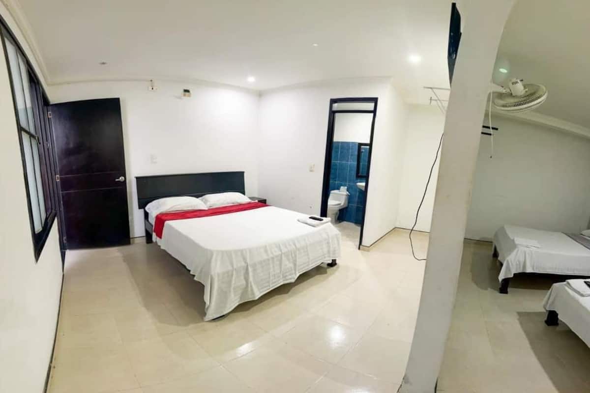 Una habitación de hotel con cama, mesita de noche, espejo, ventana y puerta.