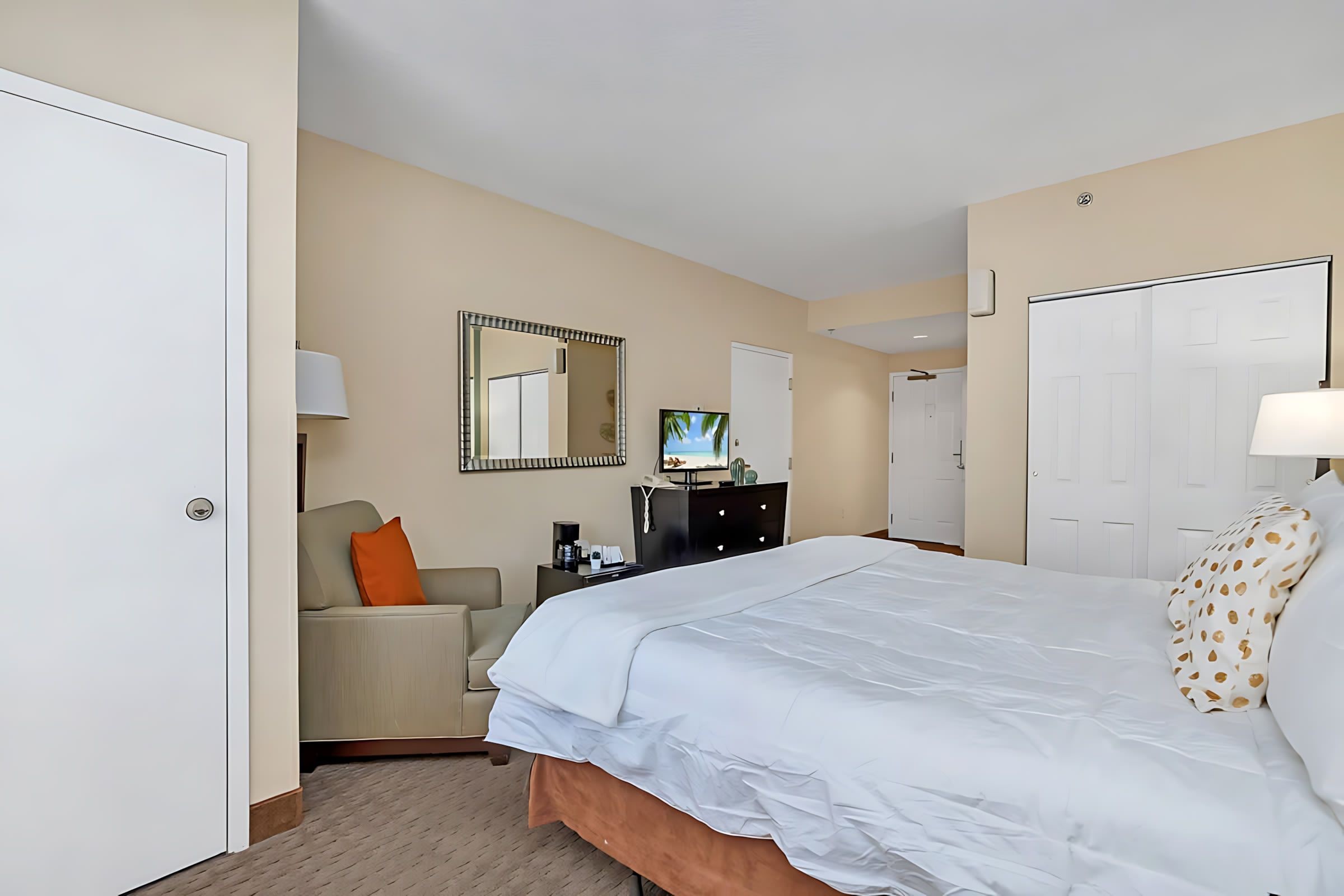 Una habitación de hotel con cama, escritorio, silla, televisor y armario.