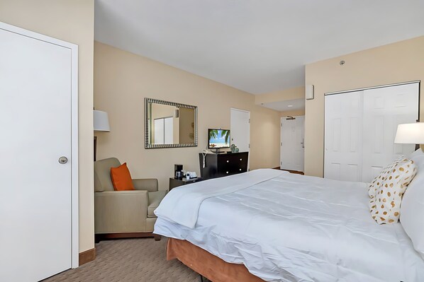 A hotel room with a bed, a desk, a chair, a TV, and a wardrobe.