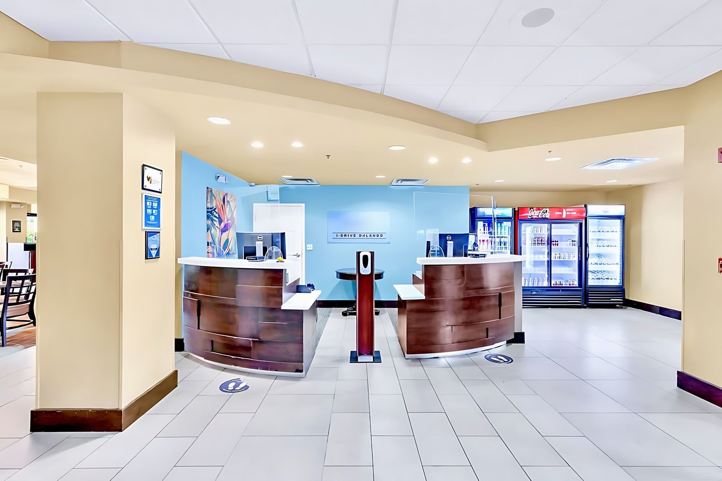 A reception area with two counters, a Coca-Cola refrigerator, and a blue wall with a sign.