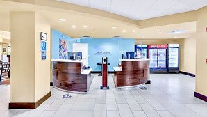A reception area with two counters, a Coca-Cola refrigerator, and a blue wall with a sign.