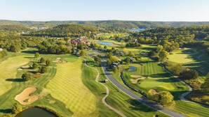 En vy över en golfbana från ovan, med flera hål, ett klubbhus och omgivande skogsområden.