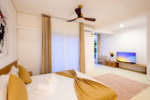 A hotel room with a bed, curtains, a ceiling fan, a TV, and a view of the outdoors. - Panda Express Guesthouse (Grand-Baie)