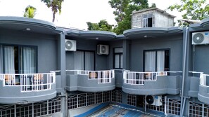 Un edifici amb diversos balcons, aparells d'aire condicionat i barana blava.