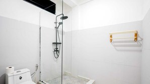 Un baño con inodoro, cabina de ducha y perchero para toallas.