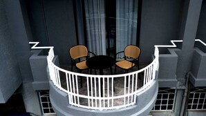 Un balcón con una mesa redonda y dos sillas, rodeado por una barandilla blanca.