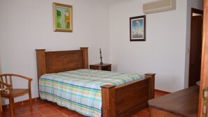 Een slaapkamer met een houten bed, nachtkastje, stoel en een dressoir.