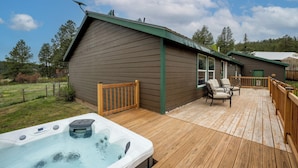 Eine Holzterrasse mit Whirlpool, Sitzgelegenheit im Freien und einem Gebäude mit Gründach.