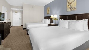 Een hotelkamer met twee bedden, een bureau, een televisie en kunstwerken aan de muur.