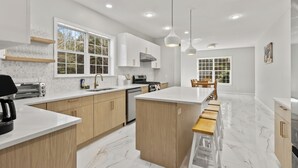 A modern kitchen with white cabinets, a central island, and pendant lighting.