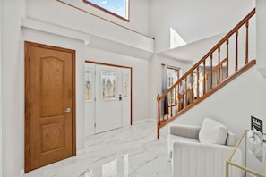 Ein geräumiger Flur mit Holztür, weißer Wand und einer Treppe mit Holzläufer.