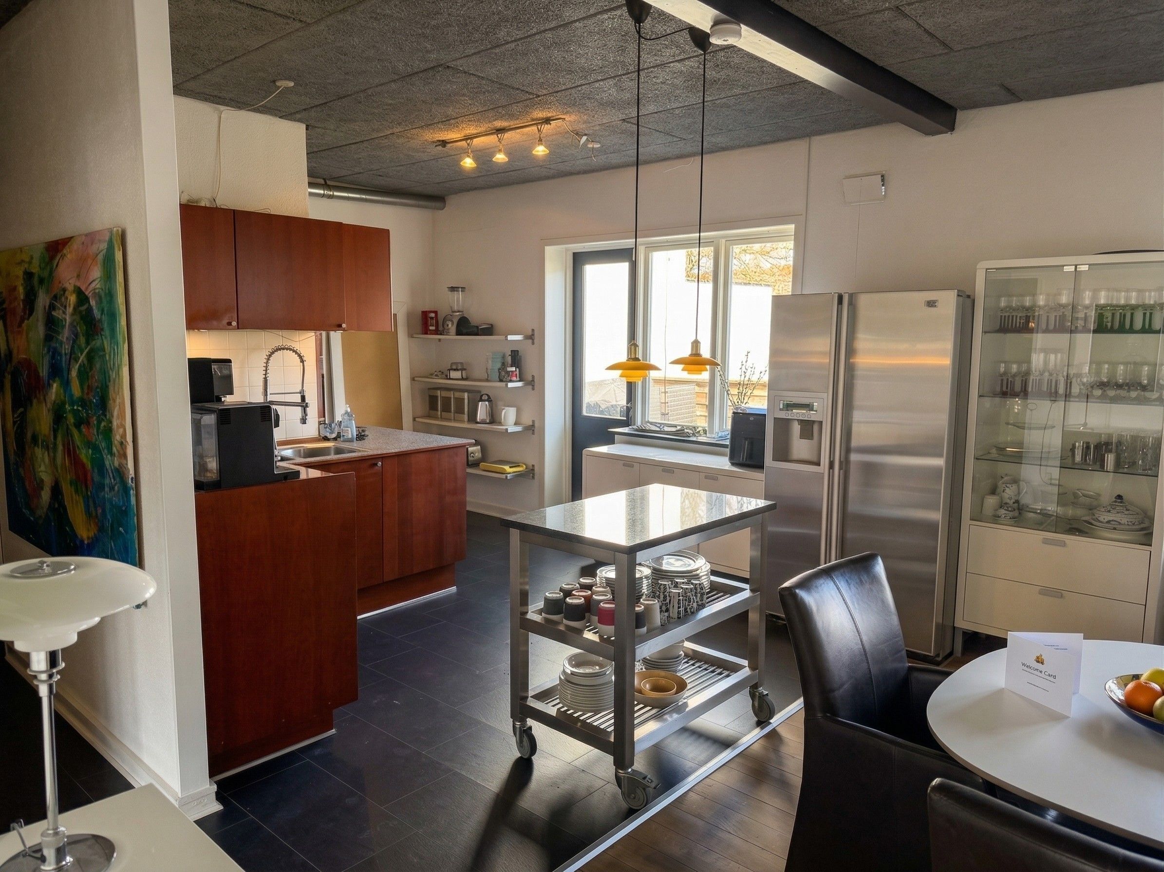 A modern kitchen with a central island, stainless steel appliances, and a dining area with a white table and black chairs.