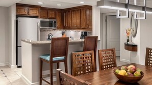 Una cucina moderna con mobili in legno, forno a microonde integrato e zona pranzo con tavolo e sedie in legno.
