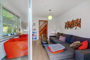A modern living room with a sofa, a glass table, and a staircase leading to another level.