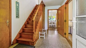 Una escalera de madera que lleva a una habitación con una puerta, un pequeño banco blanco y un letrero en la pared.