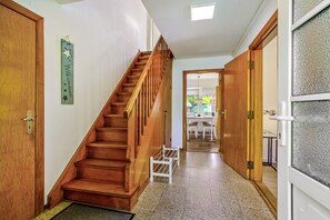 Una escalera de madera que lleva a una habitación con una puerta, un pequeño banco blanco y un letrero en la pared.