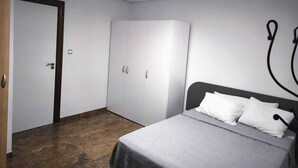 A bedroom with a bed, a wardrobe, a door, and a ceiling fan.