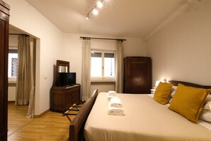 Una camera da letto con un letto, una televisione, un armadio e una finestra con tende.
