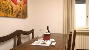 Una mesa de comedor con una botella de vino, vaso, menú y control remoto.