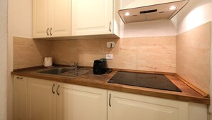 Una cocina con armarios blancos, encimera de madera, estufa integrada y horno empotrado.