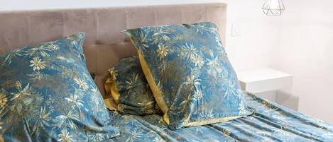 A bed with floral-patterned bedding, a headboard, and a hanging light fixture.