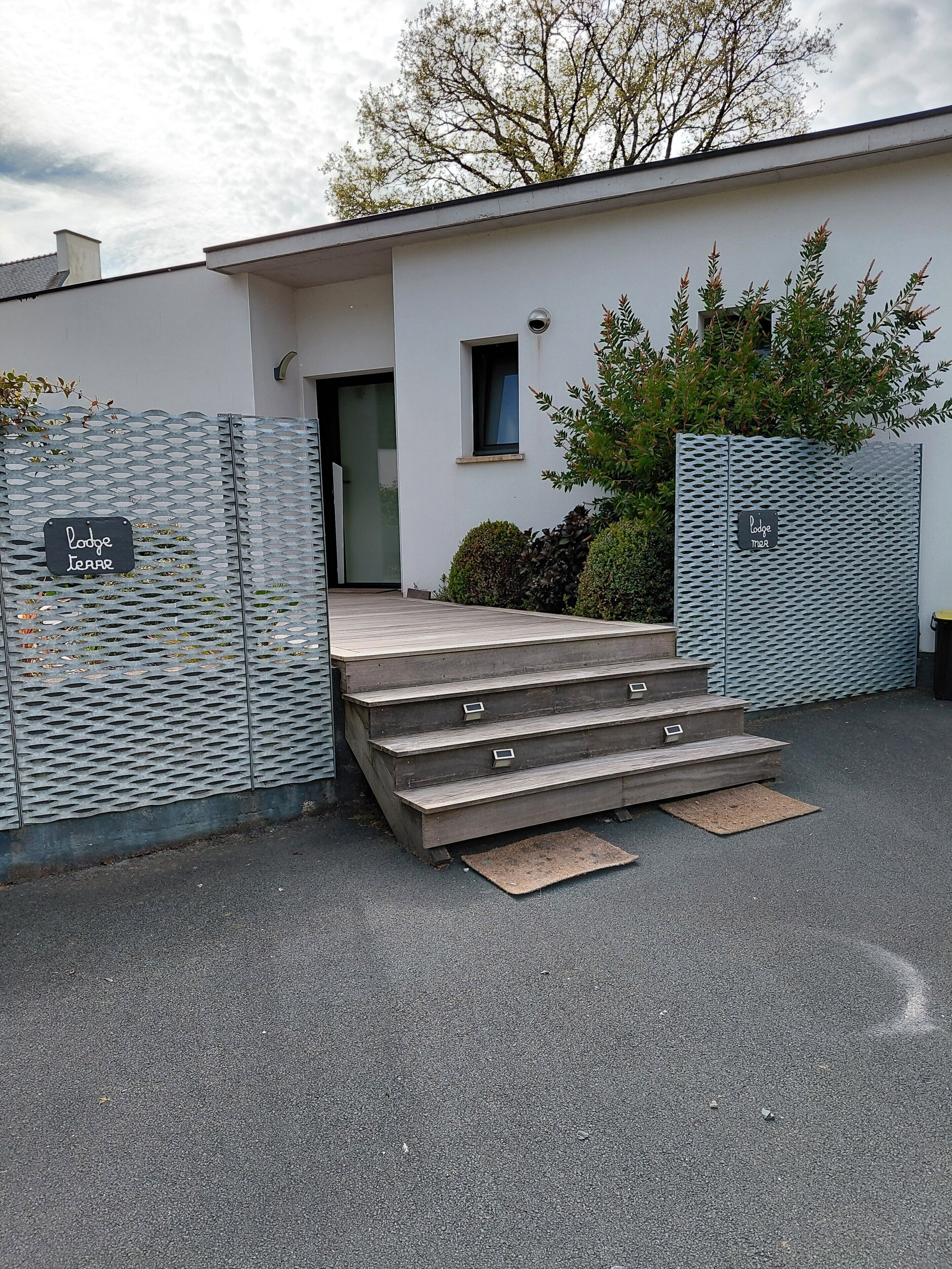 A building with a metal fence, a wooden staircase leading to a door, and a sign that reads 'Lodge Terr.'
