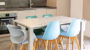 Uma cozinha moderna com uma mesa de madeira e quatro cadeiras, forno embutido e uma pia.