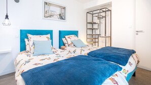 Uma cama de casal com cabeceira azul e colcha estampada com peixes coloridos.