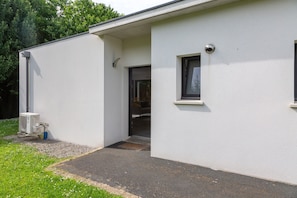 Un bâtiment moderne à l’extérieur blanc, doté d’une petite entrée et d’une fenêtre.