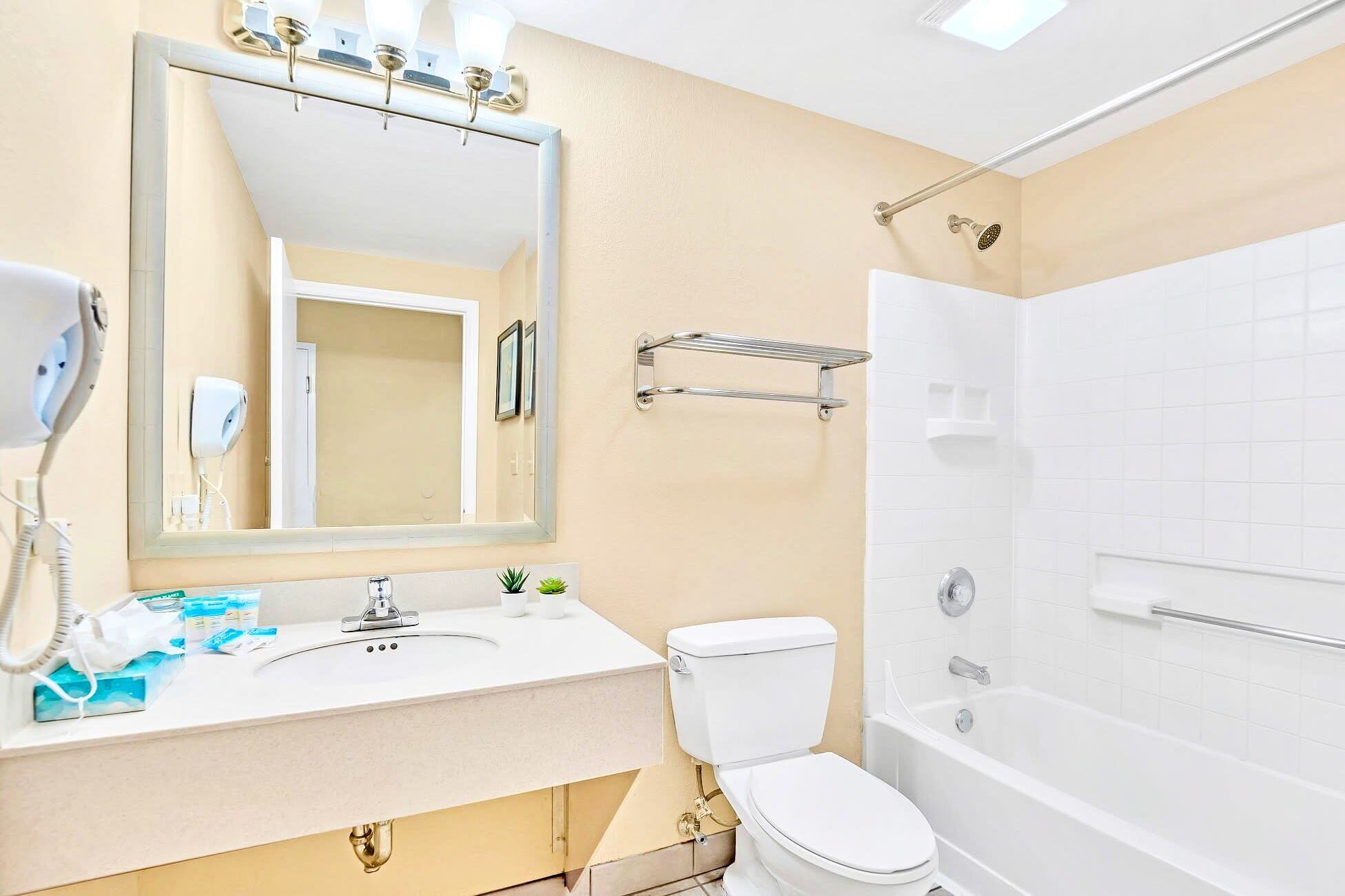 Un bagno con lavandino, specchio, water e vasca bianca.