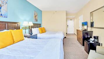 A hotel room with two beds, a dresser, a television, and artwork on the walls.