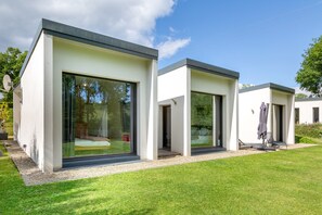 A modern, two-story house with large glass windows, a flat roof, and a well-maintained lawn. - Architect-Designed House with Jacuzzi (Concarneau)