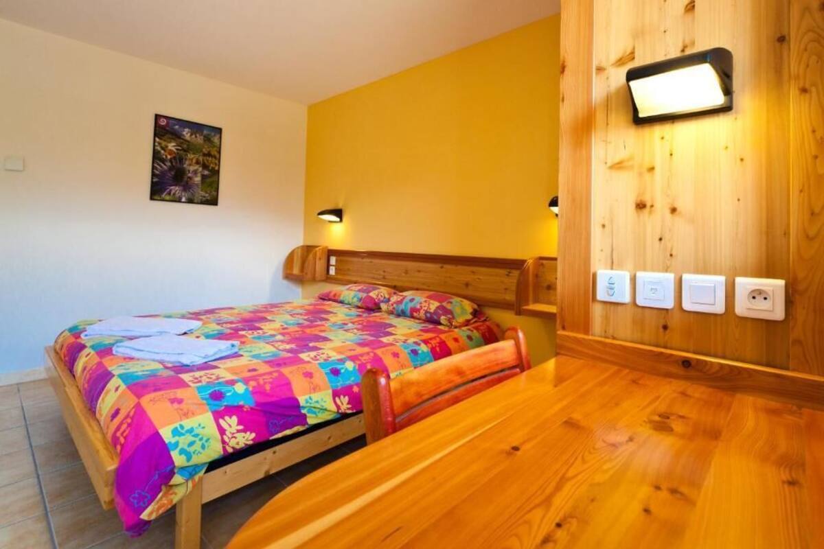 Ein Bett mit farbenfroher Steudecke, einem Holz-Kopfteil und einem Nachttisch.