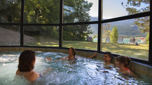 Ein Whirlpool mit Blick auf einen Wald und Berge durch große Fenster.