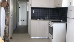 Una cocina compacta con armarios blancos, un salpicadero negro y un horno empotrado.