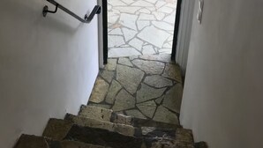 Una escalera conduce a un espacio exterior con suelo y pared de piedra.